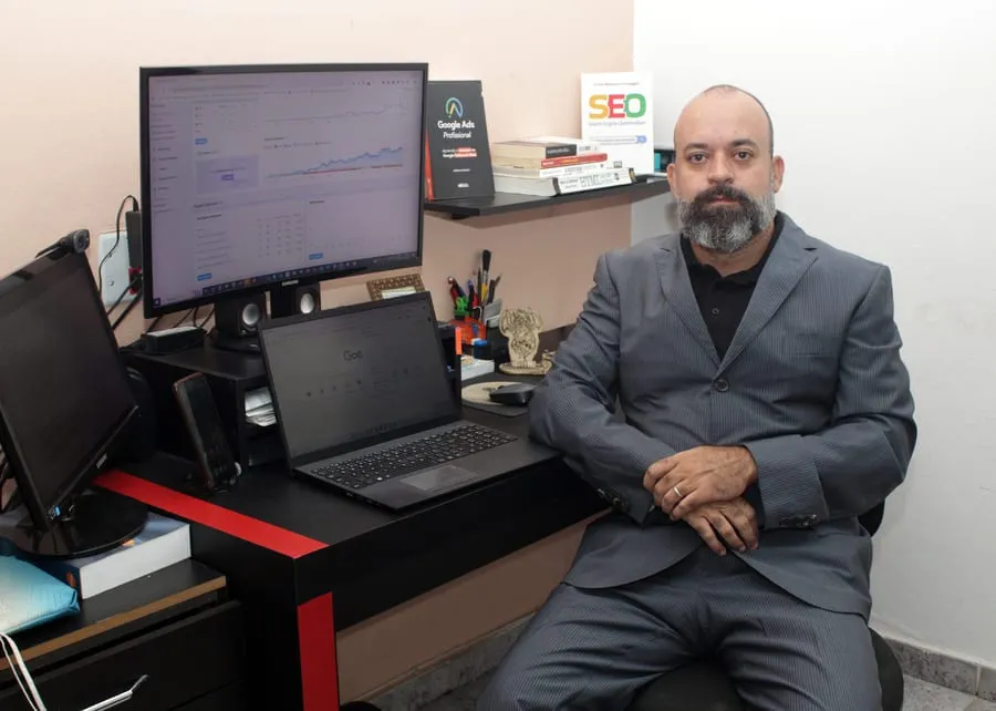 Alexandre Silva, consultor SEO local, sentado ao lado dos computadores em seu escritório