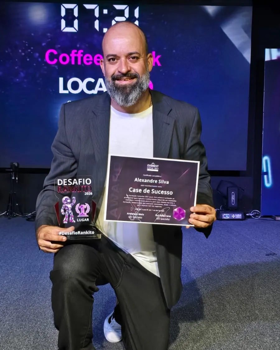 Alexandre Silva ajoelhado no palco da Formação Consultor SEO Local, segurando o troféu do Desafio Rankito e o certificado de Case de Sucesso