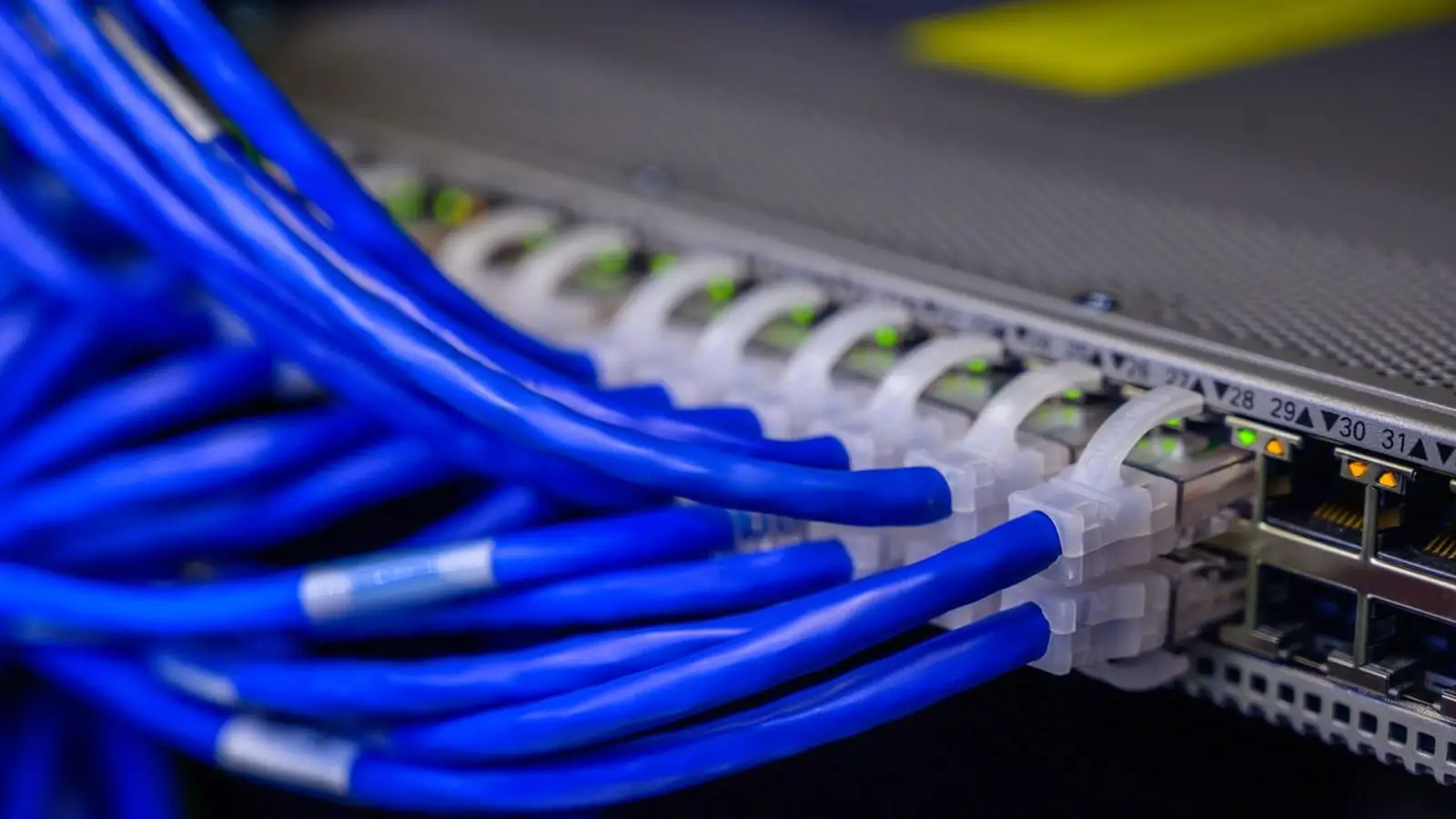 Cabos de rede azuis conectados a um switch, representando os links entre sites