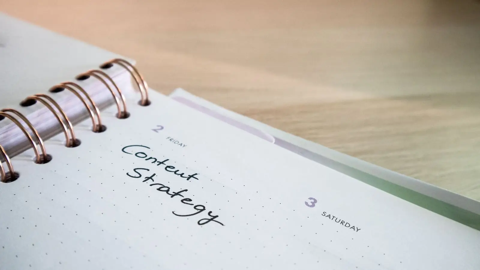 Agenda aberta com "Content Strategy" escrito à mão, sobre uma mesa de madeira